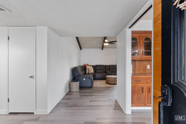 interior space with a textured ceiling, light wood-type flooring, visible vents, and baseboards