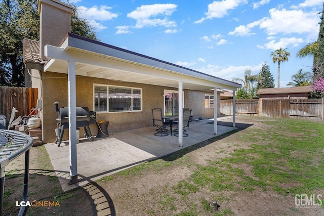 back of house with fence private yard, a chimney, a patio, and stucco siding