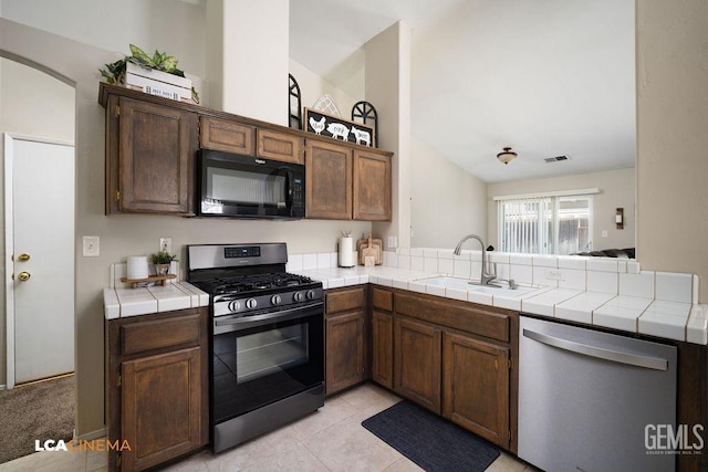 kitchen featuring visible vents, tile counters, appliances with stainless steel finishes, a peninsula, and a sink