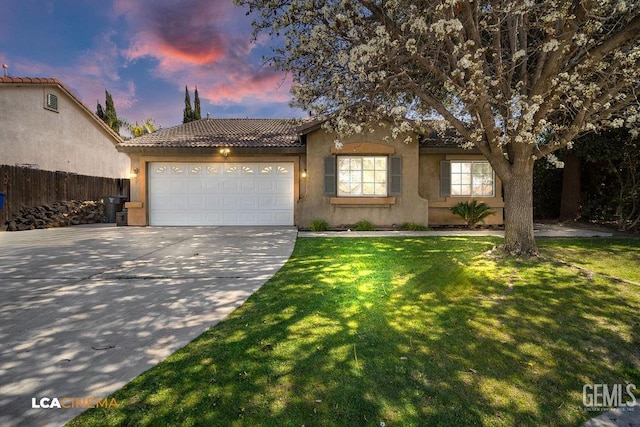 ranch-style home featuring a garage, driveway, a tile roof, a yard, and stucco siding