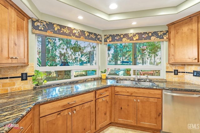 kitchen with tasteful backsplash, dark stone countertops, sink, and stainless steel dishwasher