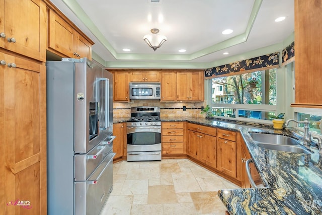 kitchen with dark stone countertops, sink, a raised ceiling, and appliances with stainless steel finishes