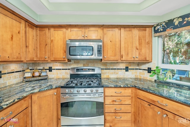 kitchen with appliances with stainless steel finishes, decorative backsplash, and dark stone counters