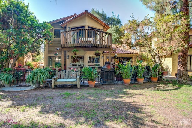 rear view of house featuring a balcony and a lawn