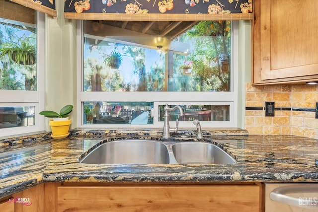 kitchen with tasteful backsplash, a healthy amount of sunlight, sink, and dark stone countertops