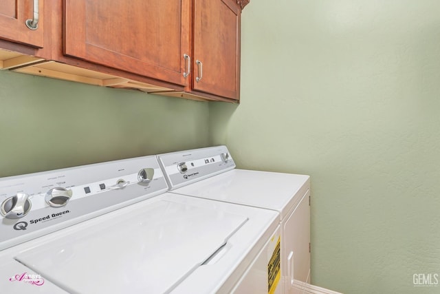 clothes washing area with cabinets and washer and clothes dryer