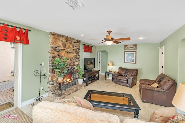 living room featuring a stone fireplace and ceiling fan