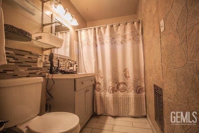 bathroom featuring decorative backsplash, tile patterned flooring, vanity, and toilet