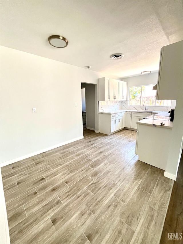 2301 Tangerine St, Bakersfield, CA 93306 - kitchen featuring light wood-type flooring, light countertops, open floor plan, and white cabinetry
