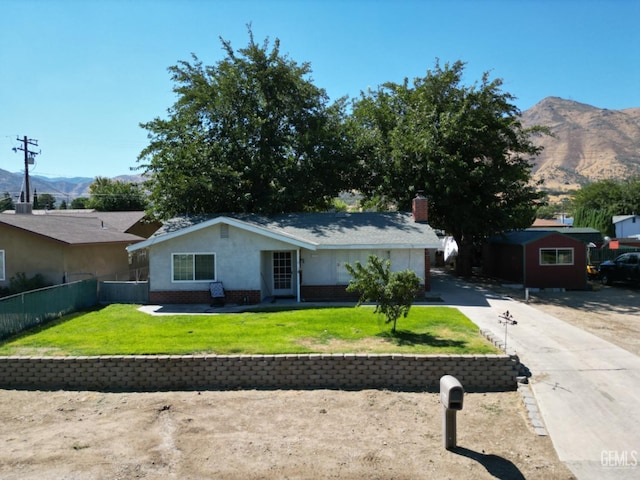 ranch-style home with a mountain view, a storage unit, and a front yard