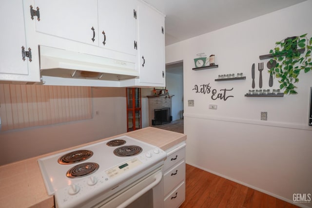 kitchen with hardwood / wood-style floors, tile countertops, white range with electric cooktop, white cabinets, and a fireplace