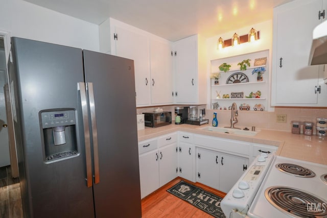 kitchen with stainless steel fridge, range, white cabinetry, and sink