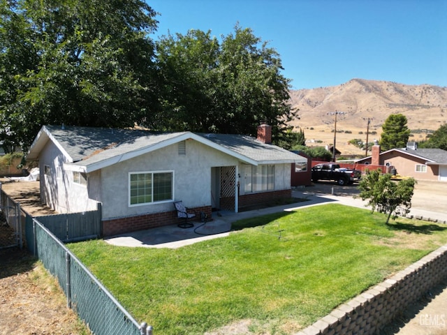 view of front facade featuring a mountain view, a patio, and a front lawn