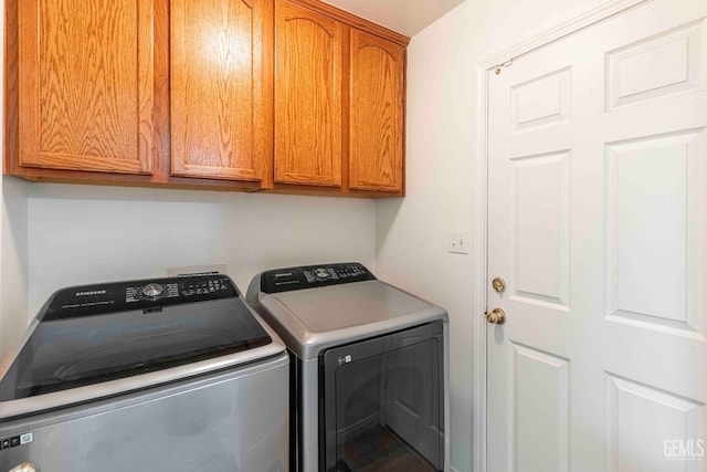 clothes washing area featuring cabinets and washing machine and clothes dryer