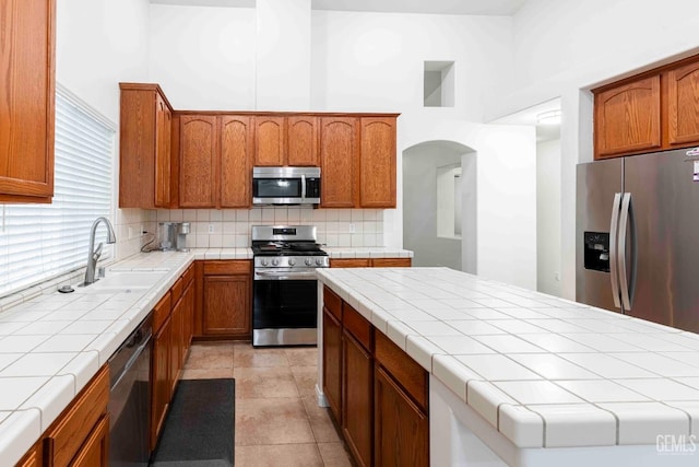 kitchen featuring stainless steel appliances, tasteful backsplash, sink, and tile countertops