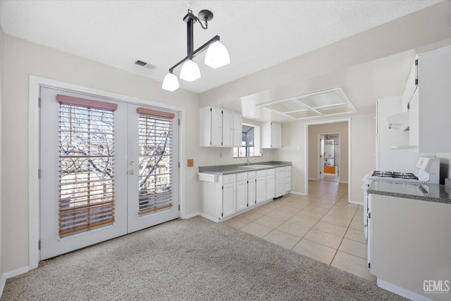 kitchen with french doors, visible vents, white cabinets, a sink, and white range with gas stovetop