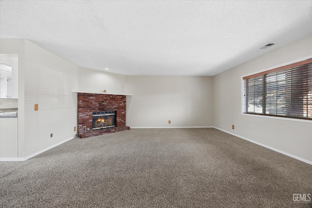 unfurnished living room with a fireplace, visible vents, carpet flooring, a textured ceiling, and baseboards