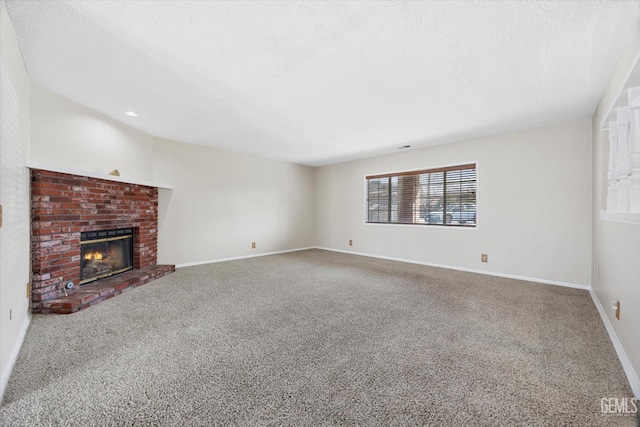 unfurnished living room with carpet floors, a fireplace, baseboards, and a textured ceiling