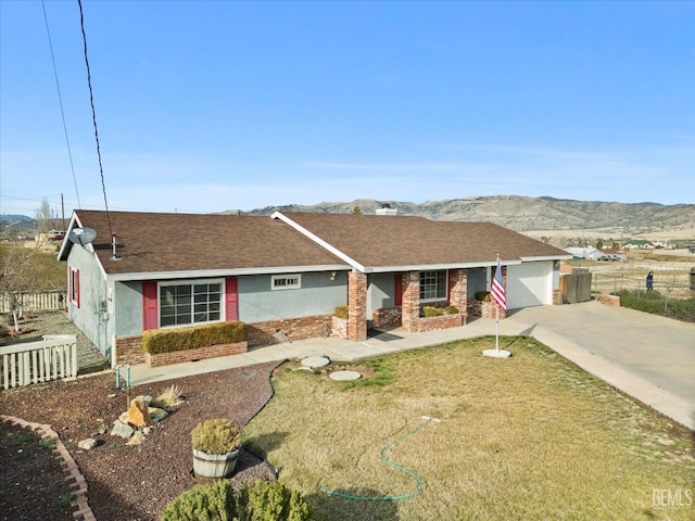 ranch-style house featuring a mountain view, a garage, brick siding, fence, and driveway