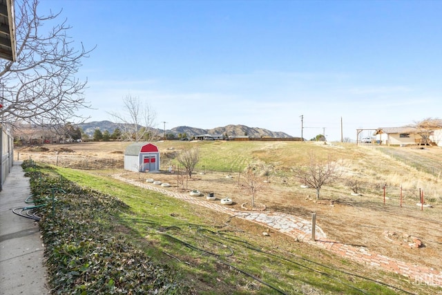 view of yard with a storage shed, a rural view, a mountain view, and an outdoor structure