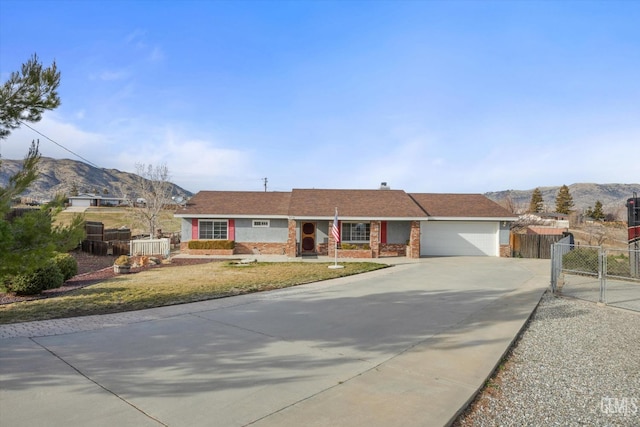 ranch-style home with driveway, a garage, a gate, fence, and a mountain view