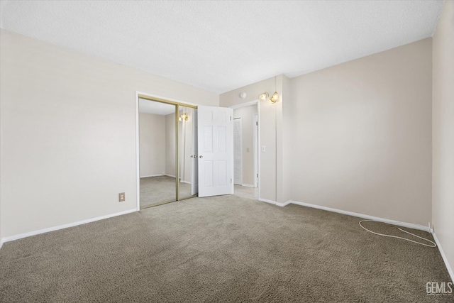 unfurnished bedroom featuring a closet, carpet flooring, a textured ceiling, and baseboards