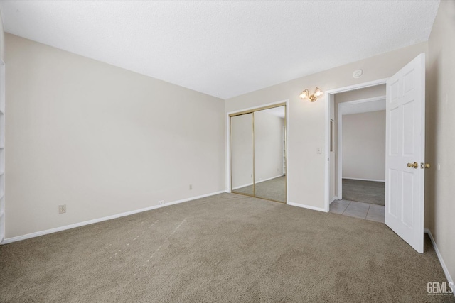 unfurnished bedroom featuring carpet, a textured ceiling, baseboards, and a closet