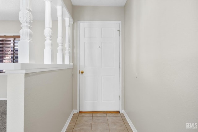 doorway to outside featuring baseboards and light tile patterned flooring