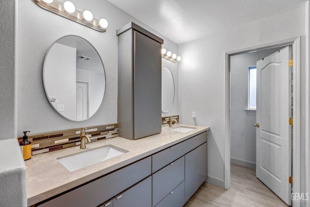 bathroom with vanity, hardwood / wood-style floors, and decorative backsplash