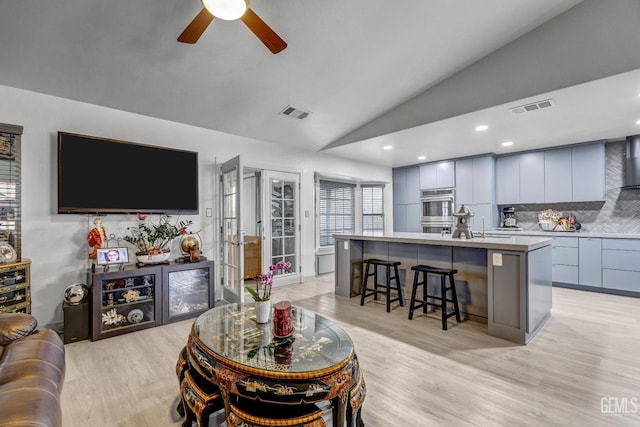 living room featuring light hardwood / wood-style flooring, vaulted ceiling, and ceiling fan