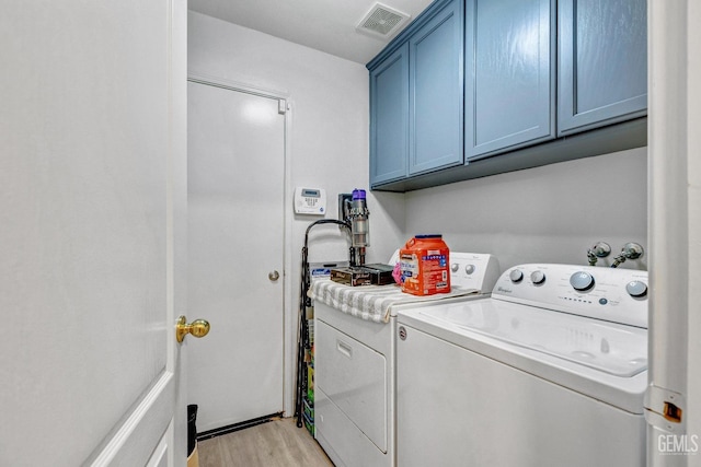 laundry area with cabinets, washer and dryer, and light wood-type flooring