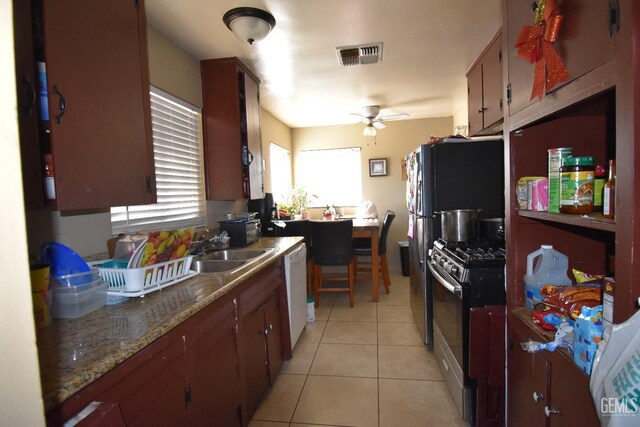 kitchen with light tile patterned floors, sink, dishwasher, ceiling fan, and stainless steel range with gas cooktop