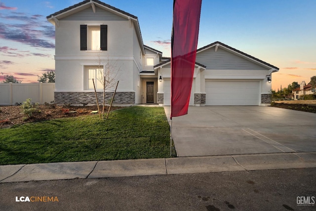 view of front of property with a front lawn, fence, driveway, stone siding, and an attached garage