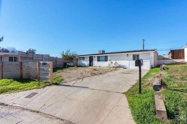 ranch-style home featuring driveway, fence, and stucco siding