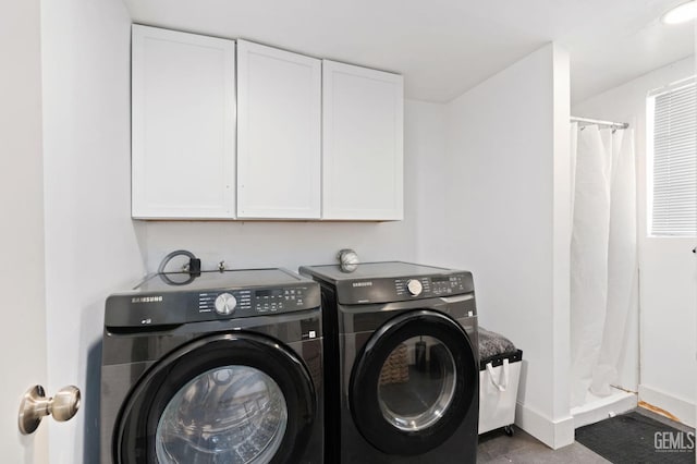 clothes washing area with baseboards, cabinet space, and washing machine and clothes dryer