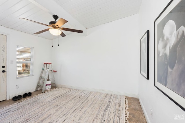 empty room with a ceiling fan, vaulted ceiling with beams, and baseboards