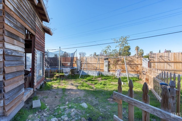 view of yard featuring a trampoline and a fenced backyard