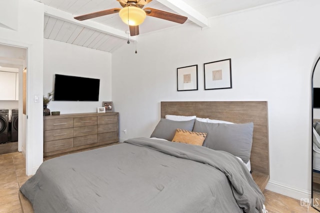 bedroom featuring ceiling fan, vaulted ceiling with beams, light tile patterned flooring, baseboards, and washer and dryer