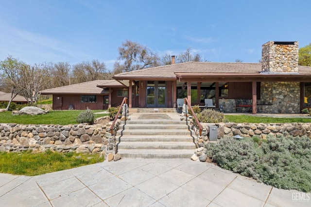 4227 Poso Flat Rd, Bakersfield, CA 93308 - single story home with a tiled roof, stone siding, french doors, and a chimney