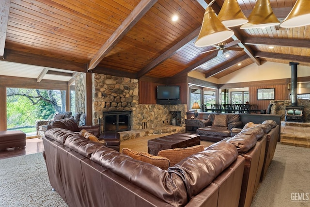 4227 Poso Flat Rd, Bakersfield, CA 93308 - carpeted living room featuring wood ceiling, a ceiling fan, a stone fireplace, a wood stove, and vaulted ceiling with beams