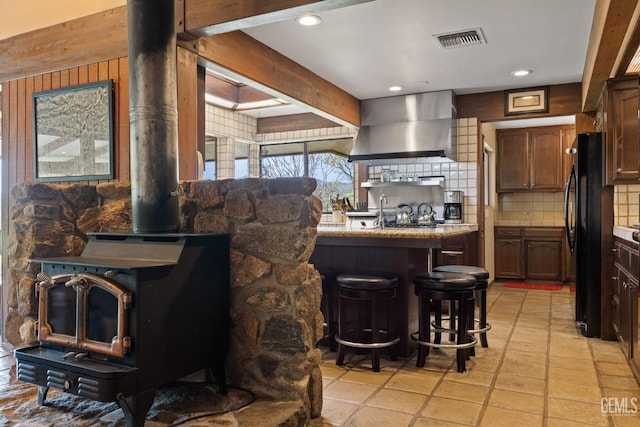 4227 Poso Flat Rd, Bakersfield, CA 93308 - kitchen with visible vents, tasteful backsplash, a wood stove, freestanding refrigerator, and wall chimney exhaust hood