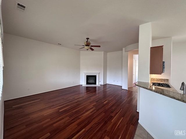 unfurnished living room featuring ceiling fan and dark wood-type flooring