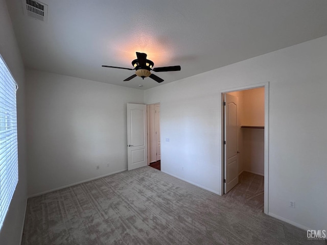 unfurnished bedroom featuring carpet floors, a spacious closet, a closet, and ceiling fan