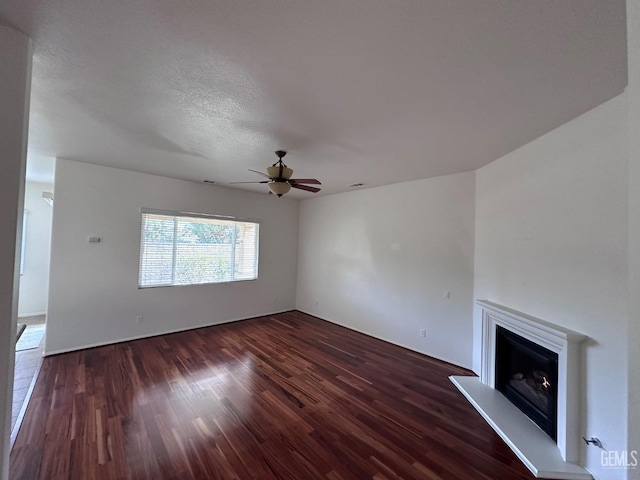 unfurnished living room with dark hardwood / wood-style floors, ceiling fan, and a textured ceiling