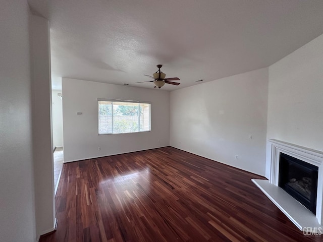 unfurnished living room with dark hardwood / wood-style floors, ceiling fan, and a textured ceiling