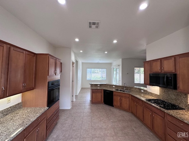 kitchen featuring light stone countertops, sink, and black appliances