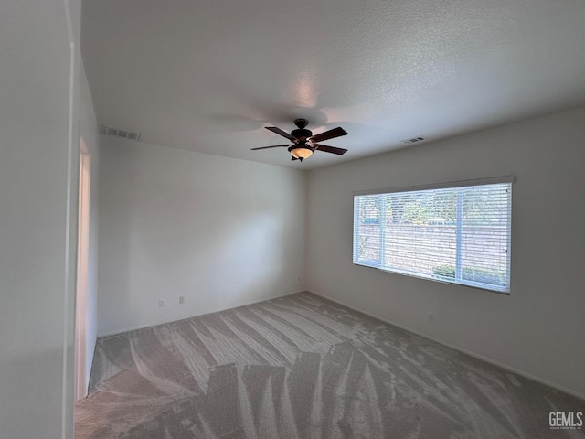 spare room featuring carpet, ceiling fan, and a textured ceiling