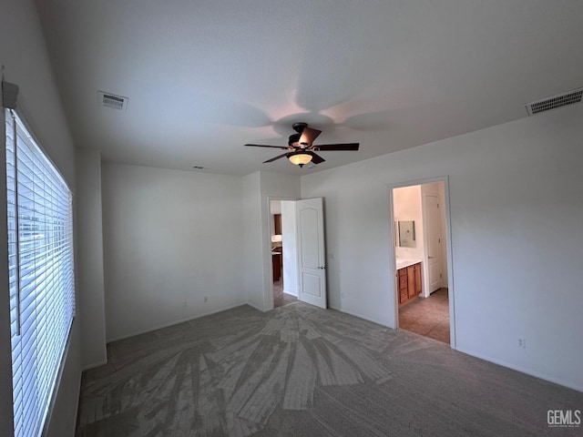 unfurnished bedroom with ensuite bath, ceiling fan, and light colored carpet