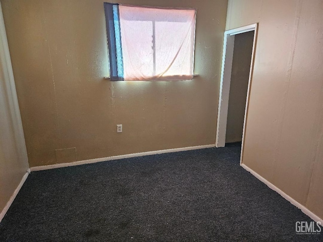 spare room featuring dark colored carpet