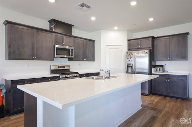 10213 Breitenbush Ave, Bakersfield, CA 93311 - kitchen with stainless steel appliances, a sink, dark brown cabinetry, dark wood-style flooring, and an island with sink